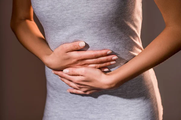 Teilbild einer Frau mit Bauchschmerzen auf dunklem Hintergrund — Stockfoto