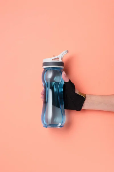 Vue recadrée de la main féminine avec bouteille de sport sur fond beige — Photo de stock