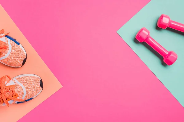 Top view of sneakers and dumbbells on pink background — Stock Photo