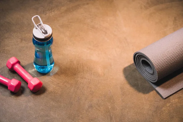 Sport equipment and bottle of water on wooden background — Stock Photo