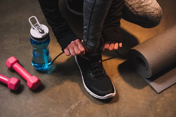 Cropped view of woman tightening laces on her sneakers — Stock Photo