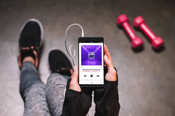 Vista recortada de la mujer sosteniendo el teléfono inteligente con aplicación de música en la pantalla - foto de stock