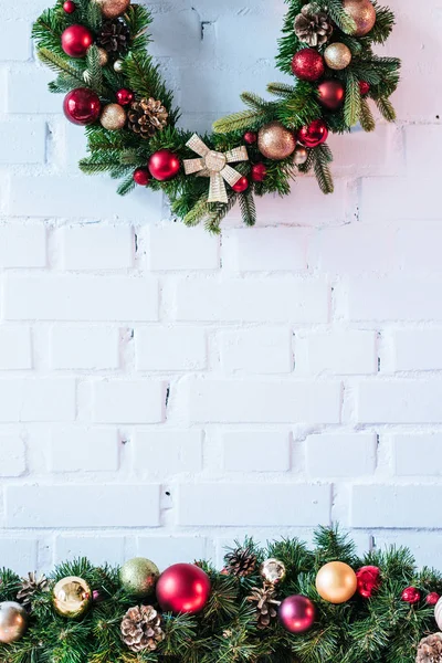 Corona de Navidad con bolas de Navidad en el fondo de la pared de ladrillo blanco - foto de stock