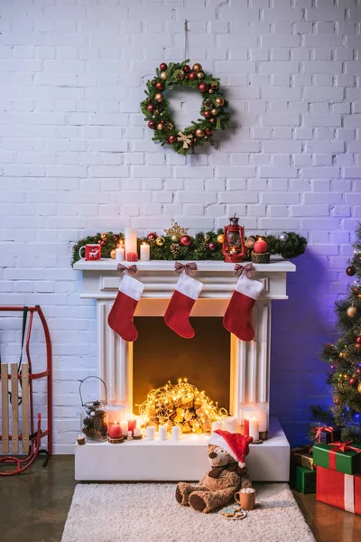 Камін з різдвяними прикрасами біля ялинки з подарунками — стокове фото