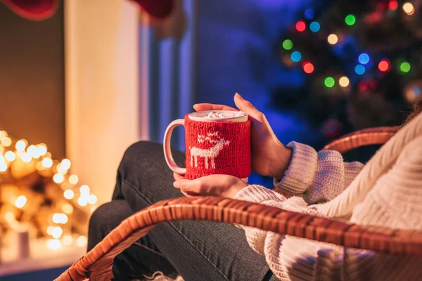 Partial view of woman with cup of coffee on christmas illuminated background — Stock Photo