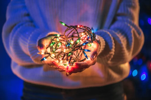 Vue partielle de la fille tenant des guirlandes brillantes lumineuses dans les mains — Photo de stock