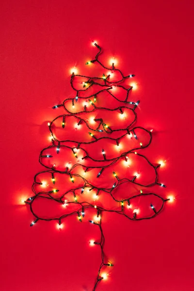 Colourful garlands in the form of christmas tree on red background — Stock Photo