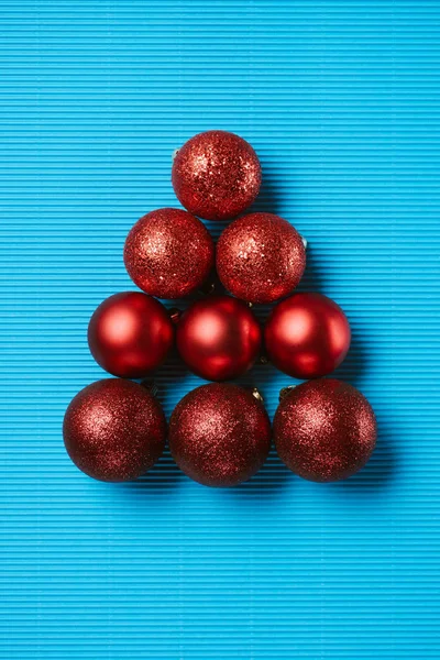 Pose plate de boules de Noël décoratives brillantes rouges sur le fond bleu — Photo de stock