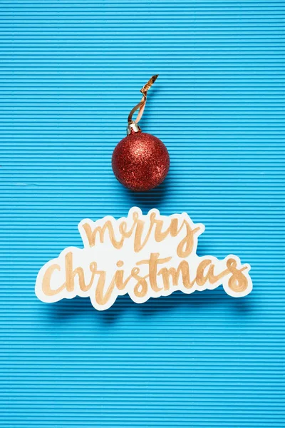 Flache Lage von frohen Weihnachten Zeichen und Weihnachtskugel auf dem blau strukturierten Hintergrund — Stockfoto