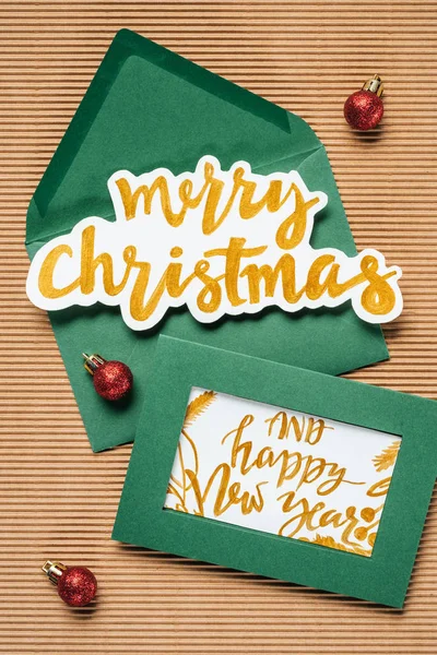 Puesta plana de sobres verdes con Feliz Navidad y Feliz Año Nuevo signo sobre el fondo texturizado - foto de stock