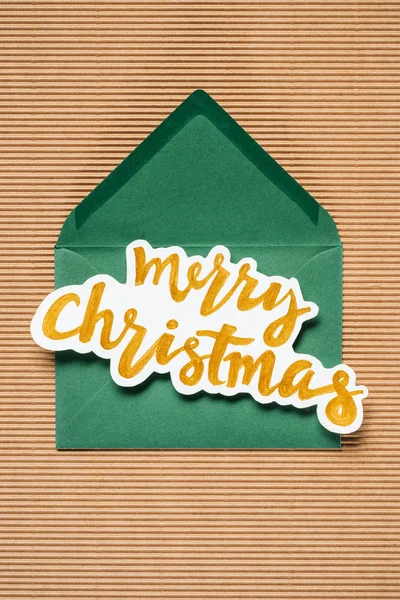 Flat lay of green envelope with yellow Merry Christmas sign — Stock Photo