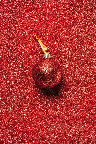 Vue de dessus de boule de Noël décorative brillante rouge sur le fond de paillettes — Photo de stock