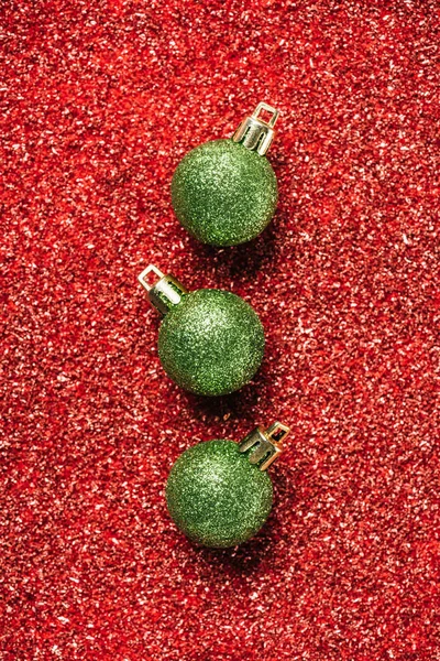 Top view of green shiny decorative christmas balls on red sequin background — Stock Photo