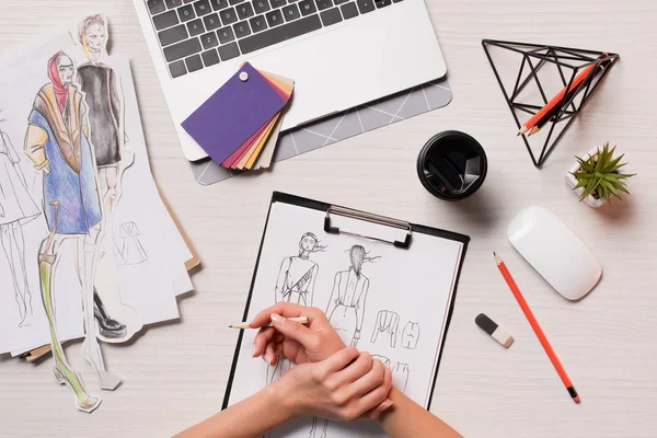 Office desk with laptop, art supplies and cropped view of designer working on sketches, flat lay — Stock Photo