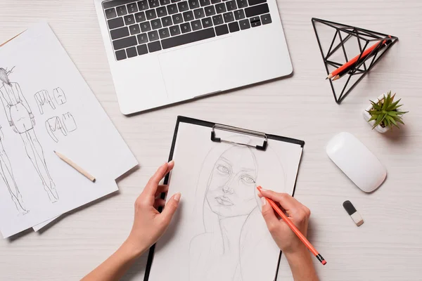 Schreibtisch im Büro mit Laptop, Kunstmaterial und ausgeschnittener Ansicht des Designers, der an Skizzen arbeitet, flache Verlegung — Stockfoto