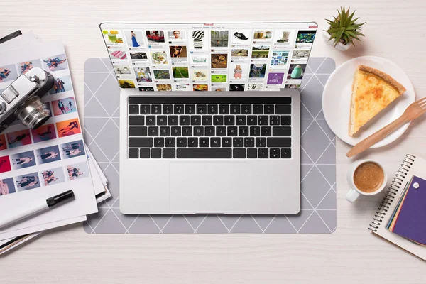 Escritorio de la oficina con el ordenador portátil con el Web site de Pinterest en la pantalla, disposición plana - foto de stock