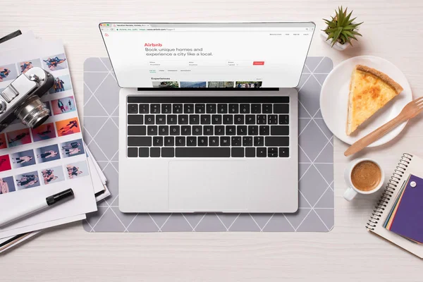 Office desk with laptop with airbnb website on screen, flat lay — Stock Photo