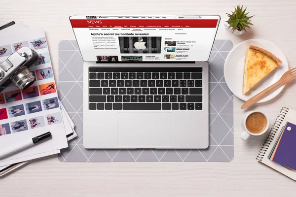 Office desk with laptop and bbc news website on screen, flat lay — Stock Photo