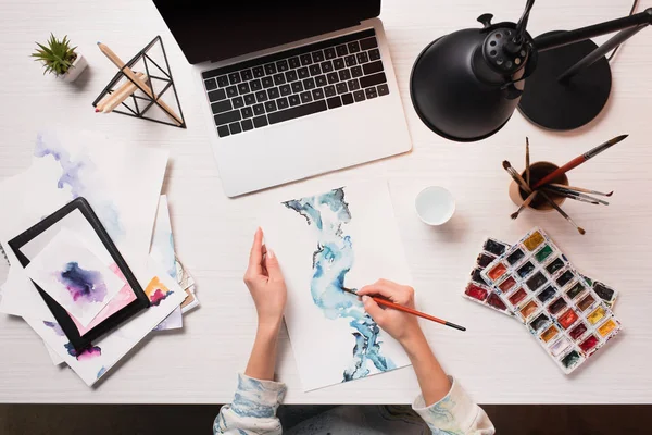 Office desk with laptop, art supplies and cropped view of designer drawing, flat lay — Stock Photo