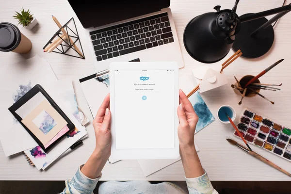 Ausgeschnittene Ansicht des Designers mit Tablet und Skype-App auf dem Bildschirm am Schreibtisch mit Kunstgegenständen, flache Lage — Stockfoto