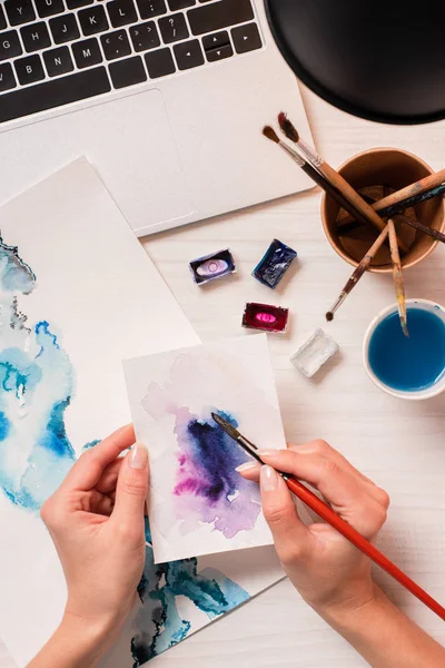 Cropped view of designer working at office desk with laptop and designer supplies — Stock Photo