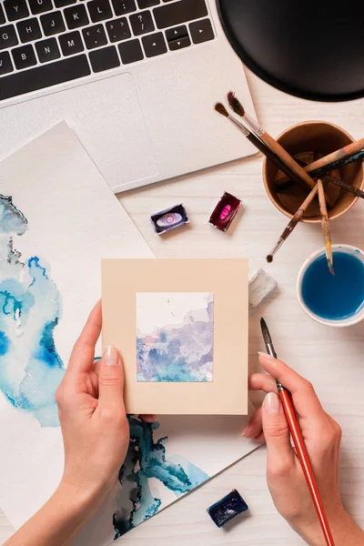 Vista recortada del diseñador que trabaja en el escritorio de la oficina con el ordenador portátil y los suministros de diseño - foto de stock