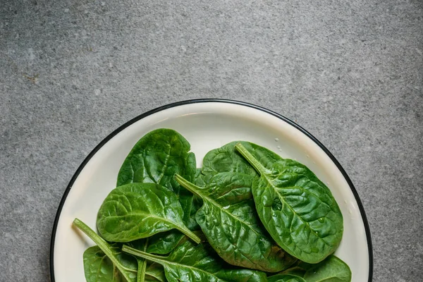 Vista superior de las hojas de espinaca fresca húmeda en el plato - foto de stock