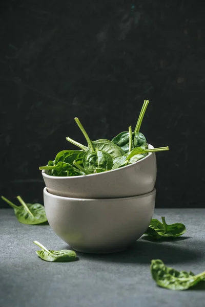 Raw organic spinach leaves in white bowls — Stock Photo