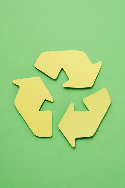 Vue du dessus du panneau jaune de recyclage avec des flèches sur fond vert — Photo de stock