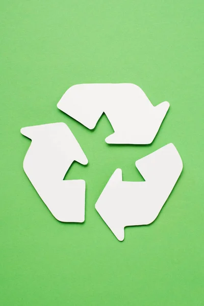 Top view of white trash recycle sign with arrows on green background — Stock Photo