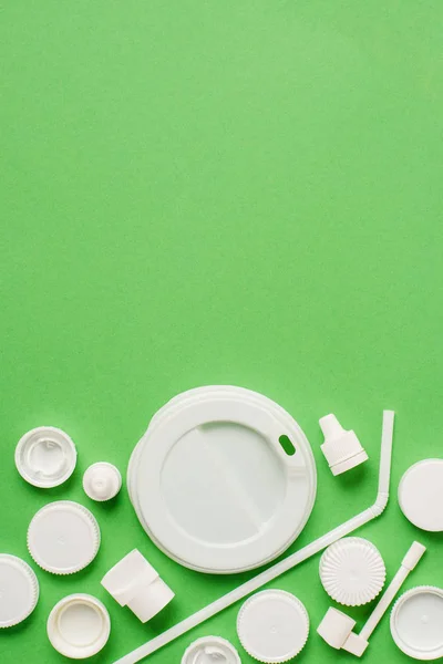 Vue du dessus des bouchons de bouteille jetables en plastique, de la paille à boire et du couvercle pour boisson sur fond vert — Photo de stock