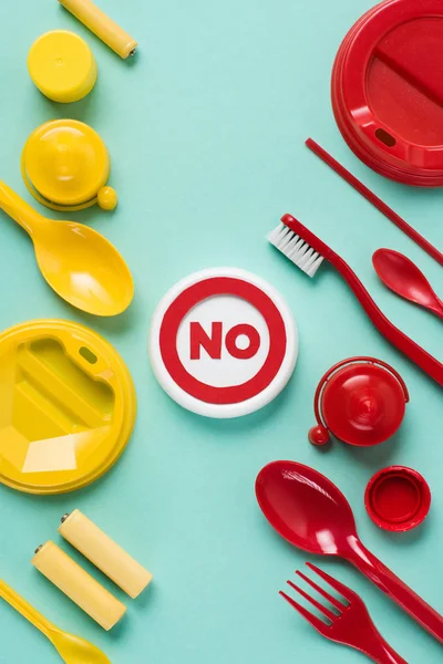 Vue du dessus d'aucun signe et déchets plactiques rouges et jaunes jetables sur fond bleu — Photo de stock