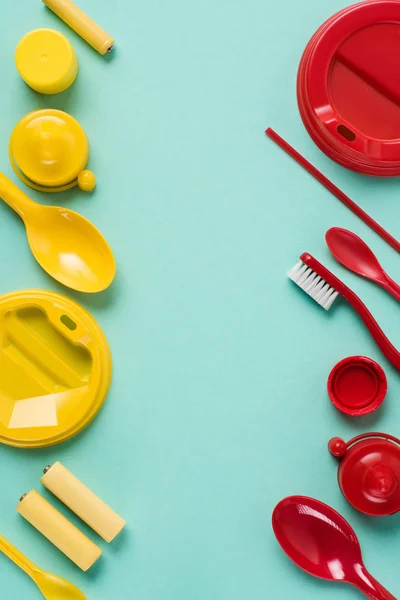 Flat lay com vermelho e amarelo descartáveis produtos de plástico dispostos em fundo azul — Fotografia de Stock