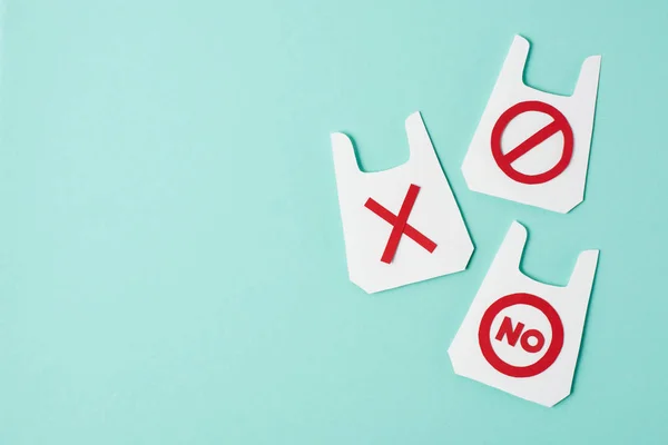 Tres modelos de paquetes de papel con signos de no y prohibición sobre fondo azul - foto de stock