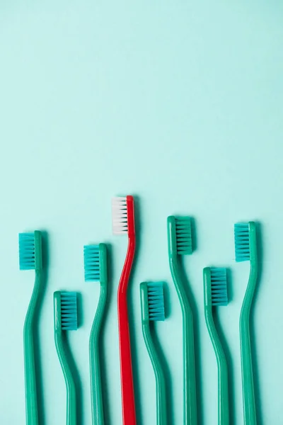 Vista superior de escovas de dentes coloridas de plástico dispostas em fundo azul — Fotografia de Stock