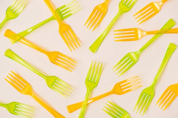 Vista dall'alto di forchette di plastica arancione e verde su sfondo rosa — Foto stock
