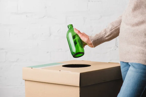 Partial view of woman throwing glass bottle in trash bin — Stock Photo