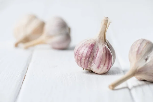 Knoblauchzwiebeln auf weißem Holztisch — Stockfoto