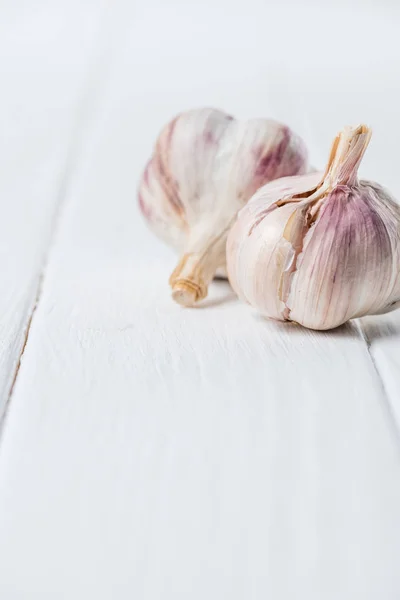 Zwei Knoblauchknollen auf weißem Holztisch — Stockfoto