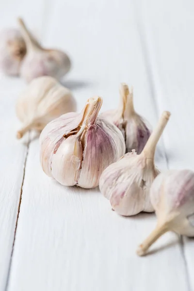 Several ripe garlic heads on white wooden table — Stock Photo