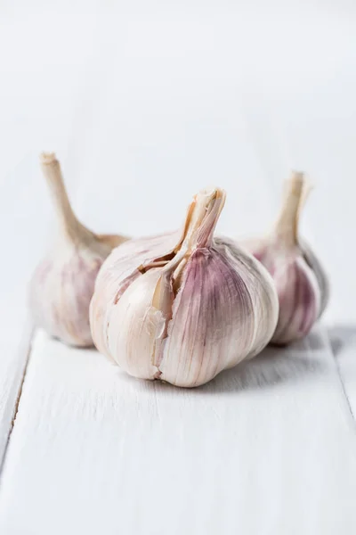 Reife Knoblauchköpfe auf weißem rustikalen Tisch — Stockfoto