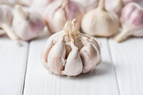 Ripe garlic bulb with cloves on white rustic table — Stock Photo