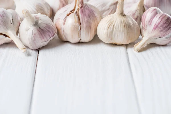 Ripe garlic heads on white rustic cook table — Stock Photo