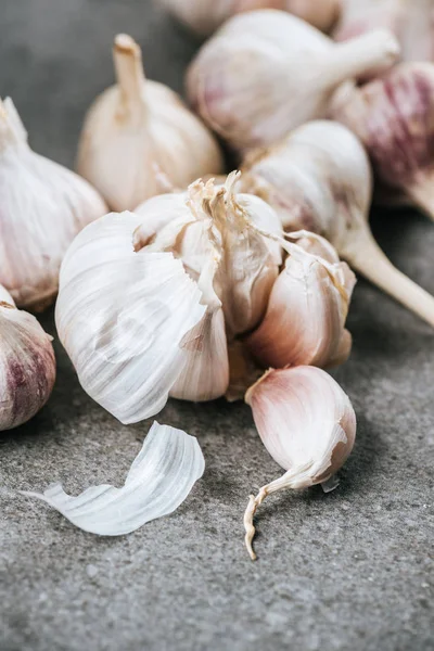 Garlic bulbs and peeled cloves on grey textured surface — Stock Photo