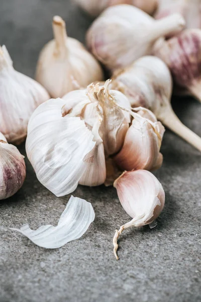 Bulbos de ajo y clavos pelados sobre una superficie texturizada gris - foto de stock