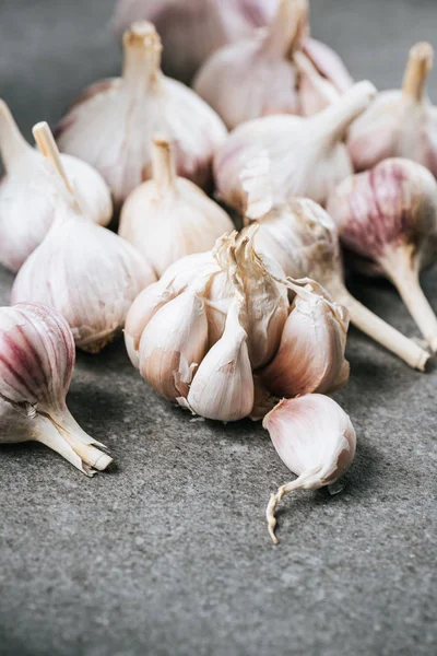 Bulbs of garlic and peeled cloves on grey textured surface — Stock Photo