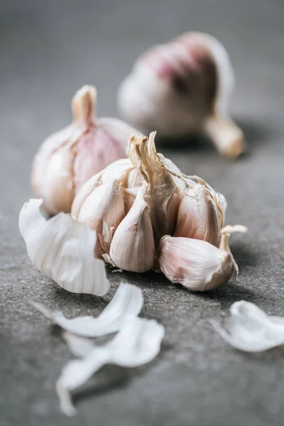 Vista ravvicinata di bulbi di aglio maturi e buccia su superficie grigia — Foto stock