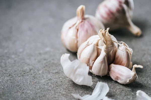 Nahaufnahme von Knoblauchzwiebeln und -schalen auf grauem Hintergrund — Stockfoto