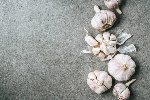 Top view of garlic bulbs and husk on grey background with copy space — Stock Photo
