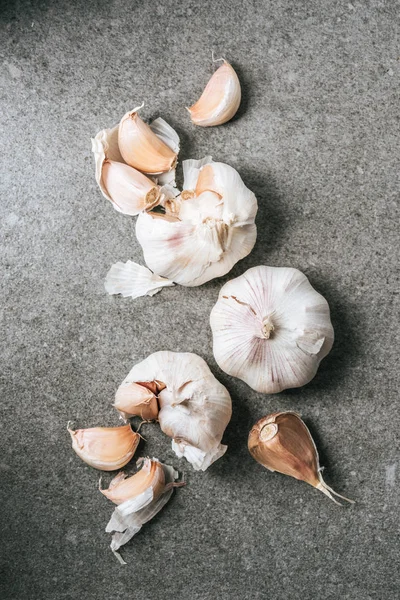 Top view of ripe bulbs and cloves of garlic on grey stone table — Stock Photo